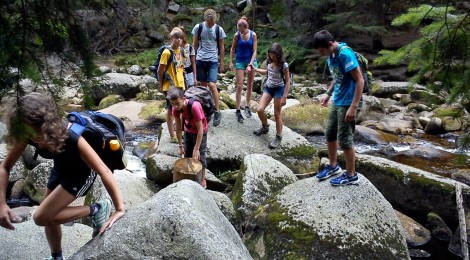 Jugendliche auf großen Steinen im Fluss