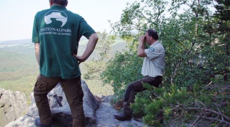 Zwei Ranger, einer mit Fernglass erfassen die Population der Wanderfalken im Natioalpark