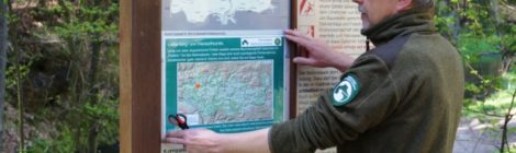 Ein Ranger hängt eine Karte an einer Infotafel auf.
