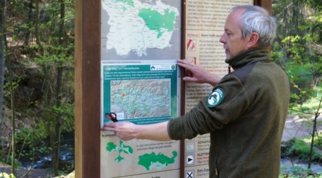 Ein Ranger hängt eine Karte an einer Infotafel auf.